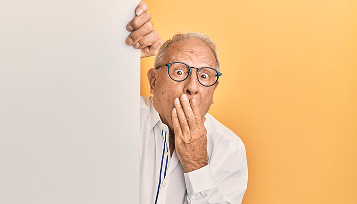 Shocked man peeking out from behind a wall - will your power bill increase soon? 